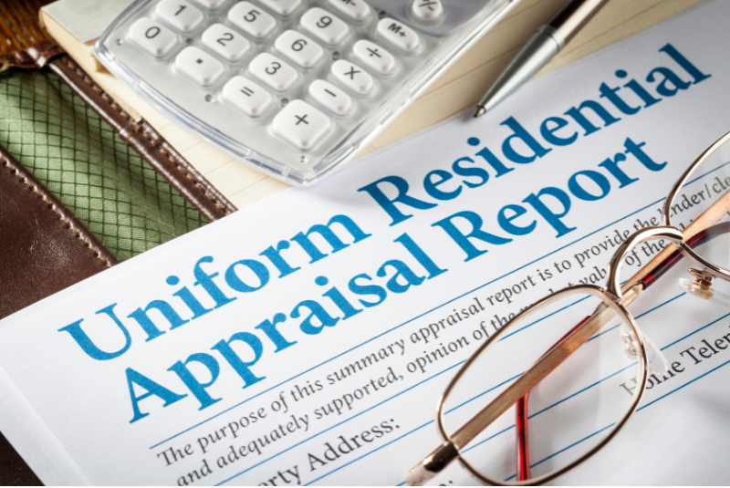 Uniform residential appraisal report laying on top of computer keyboard