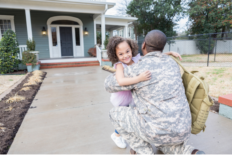 Military member welcoming young daughter in front of home