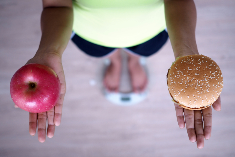 person holding an apple and a hamburger depicting vast differences when comparing va loan vs traditional mortgages